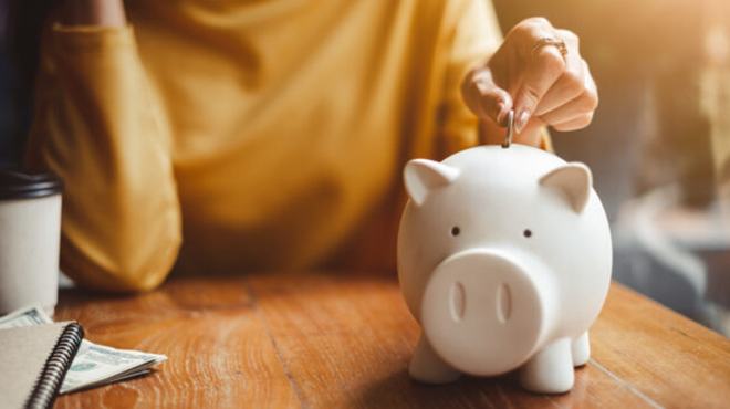 A Person Putting a Coin in a Piggy Bank