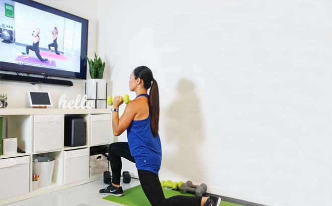 A Woman Working Out at Home to a Video