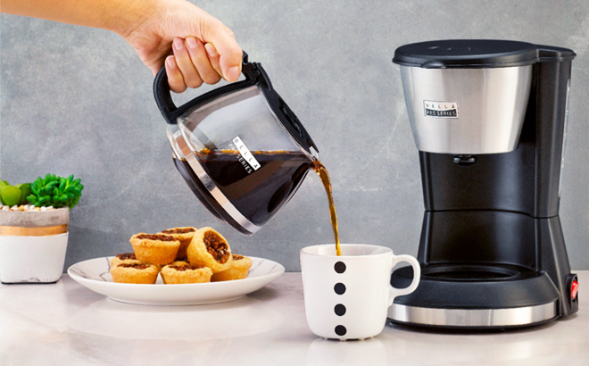 A Woman Pouring Coffee from Bella Pro Series 5 Cup Coffee Maker on a Kitchen Countertop