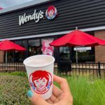 A Person Holding a Coffee Cup in Front of Wendy's