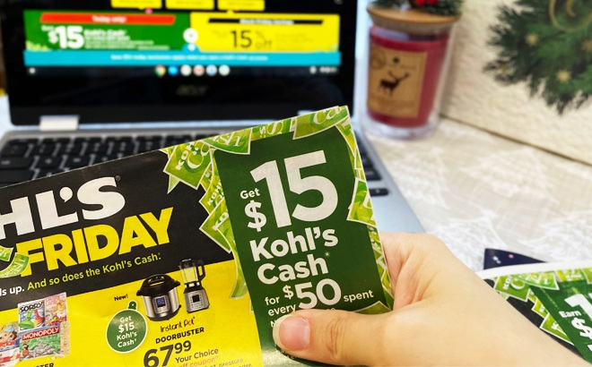 Hand Holding a Kohls Black Friday Ad in Front of a Laptop