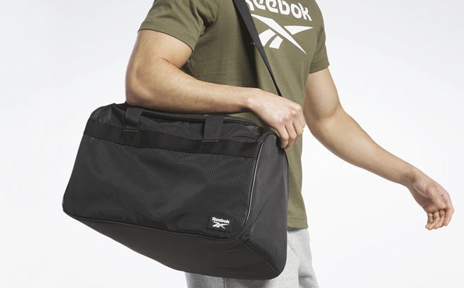 A Man Carrying Reebok Warrior II Duffel Bag Small in Black Color