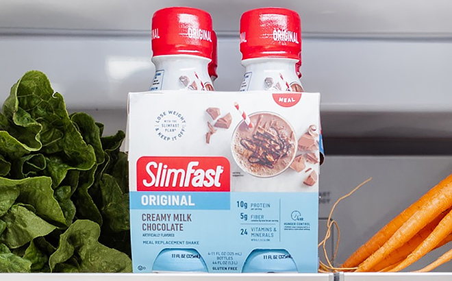 A Pack of Four SlimFast Creamy Milk Chocolate Drink Inside Fridge with Vegetables on the Side