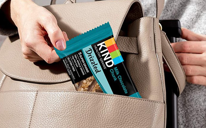 A Womens Hand Putting Kind Drizzled Bar in a Bag