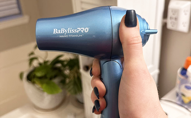 Hand Holding BaBylissPRO Nano Titanium Travel Dryer in Blue Color