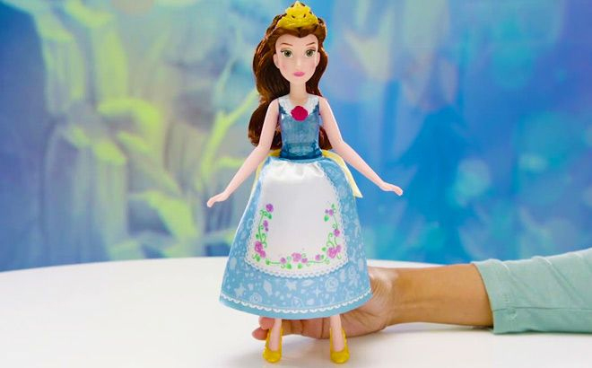 Hand Holding Disney Princess Spin and Switch Belle Doll on a Table