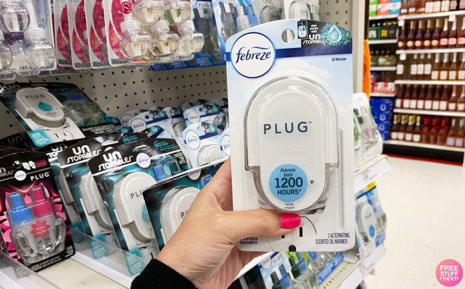 Hand Holding Febreze Plug Warmer in Front of a Store Shelf