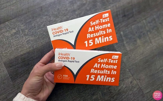 Hand Holding Two Boxes of iHealth Covid 19 Antigen Rapid Tests