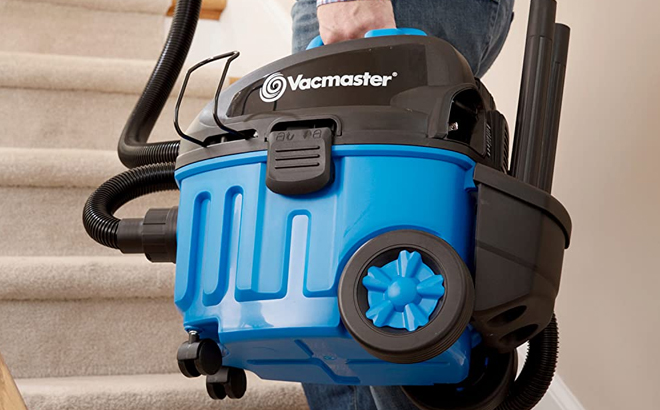 Man Holding Vacmaster Wet and Dry Vacuum and Walking Up the Stairs