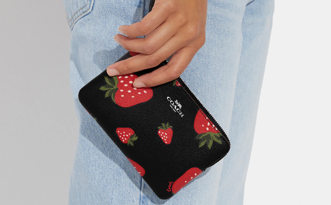 Woman Carrying Coach Outlet Corner Zip Wristlet With Wild Strawberry Print