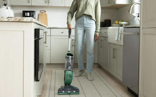 a Person Using a Shark FreeStyle Pro Cordless Vaccum on a Kitchen Floor