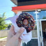 Hand Holding Dunkin Donut in Front of the Store