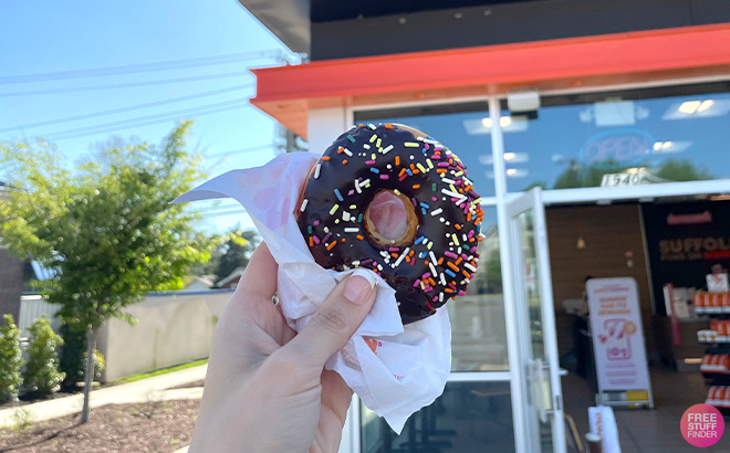 Hand Holding Dunkin Donut in Front of the Store