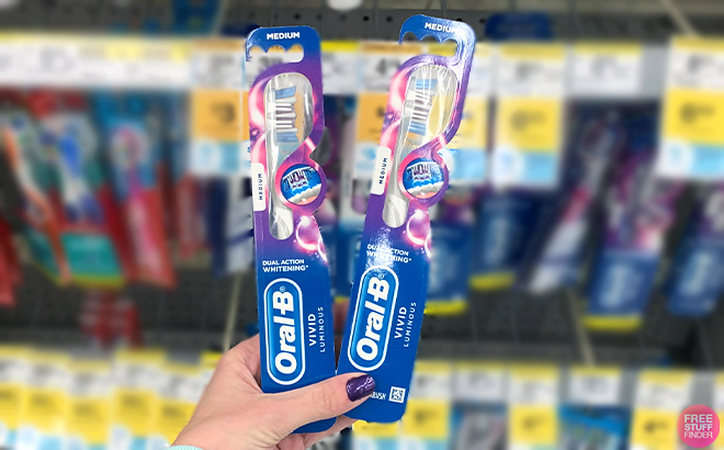 Hand Holding Two Oral B Toothbrush at Walgreens