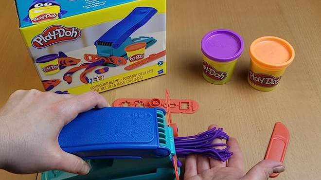 A Person Playing with Play Doh Shape Making Machine