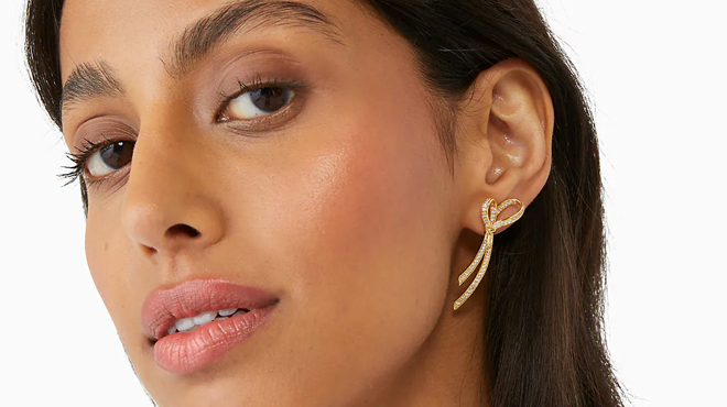 A lady wearing Kate Spade All Tied Up Pave Drop Earrings