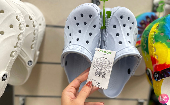 Hand Holding the Tag on Crocs Baya Clogs in Mineral Blue Color