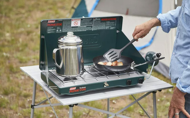 a Person Cooking with a Coleman Matchlight 10 000 BTU 2 Burner Propane Stove