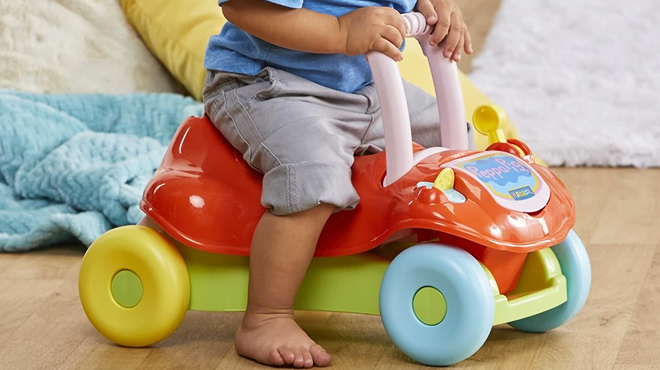 A Kid Sitting on Playskool Peppa Pig 2 in 1 Ride On Walker Toy