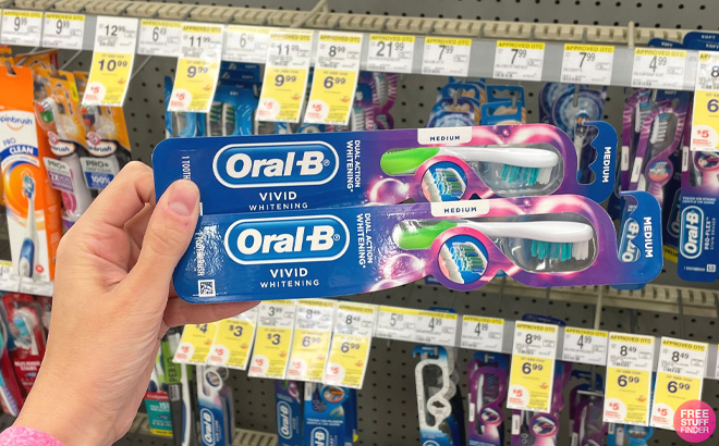 Woman Holding 2 Oral B Vivid Whitening Toothbrushes