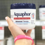 A Hand Holding Aquaphor Healing Ointment Jar