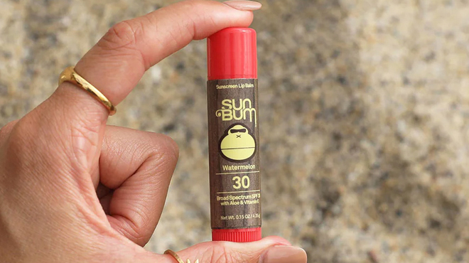 A Hand Holding Sun Bum SPF 30 Sunscreen Lip Balm in Watermelon Flavor