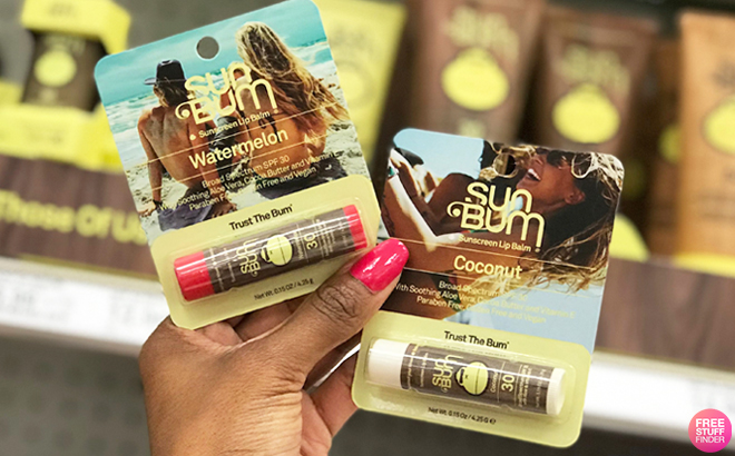 A Hand Holding Two Sun Bum Lip Balms