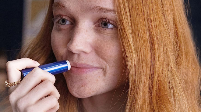 A lady applying Aquaphor Lip Repair Stick on her lips