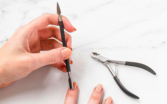 Hand holding Amazon Basics Cuticle Nipper and Pusher set for Nails