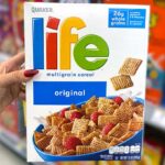 Hand holding one Quaker Life Breakfast Cereal Pack