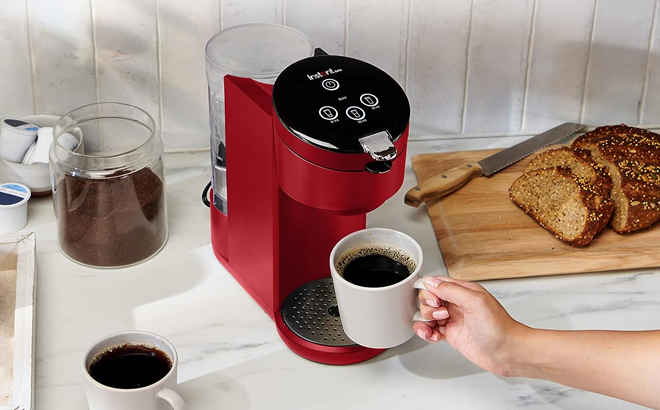 Woman Holding Coffee Cup in Front of Instant Solo Single Serve Coffee Maker