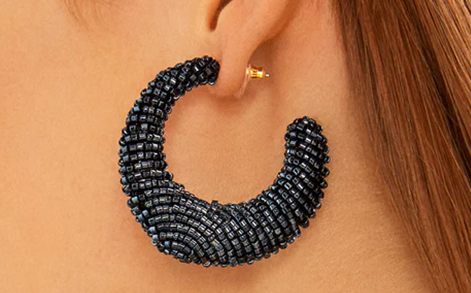 Woman is Wearing a BaubleBar Callie Earrings in Black color