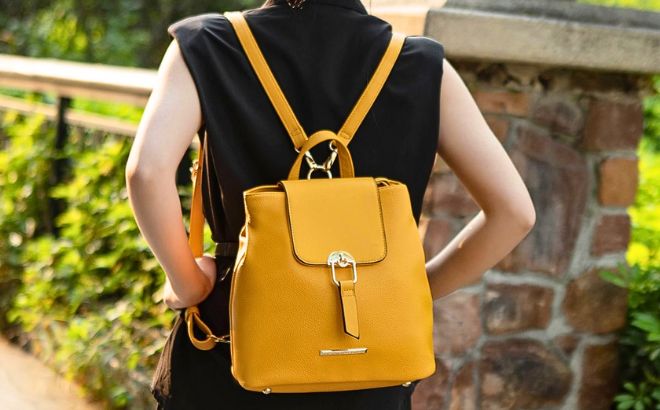 Woman is Wearing a Ingrid Vegan Leather Womens Convertible Backpack in a Yellow color