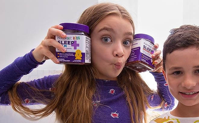 a Girl Holding Two Bottles of Natrol Kids Gummies 60 Count