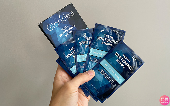 Hand Holding Gloridea Teeth Whitening Strips in Room