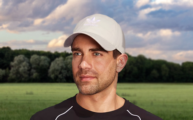 Man Standing in a Field and Wearing the Adias Relaxed Strap Back Hat in Wonder White 2