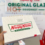 a Hand Holding a Box of Krispy Kreme Doughnuts