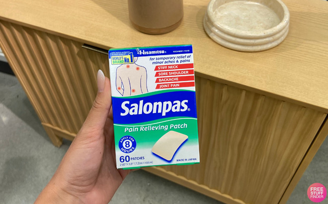 A Person Holding a Salonpas 60 Count Pain Relieving Patch in Front of Table