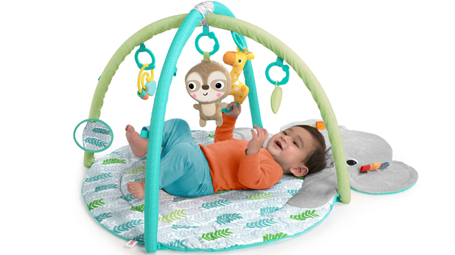 A baby lying on a Bright Starts Baby Gym and Tummy Time Play Mat