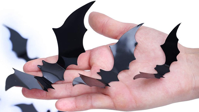 A hand holding Diyasy 120 Piece Bats Wall Decors