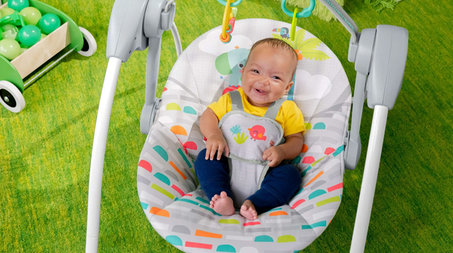 A smiling baby on a Bright Starts Portable Compact Baby Swing