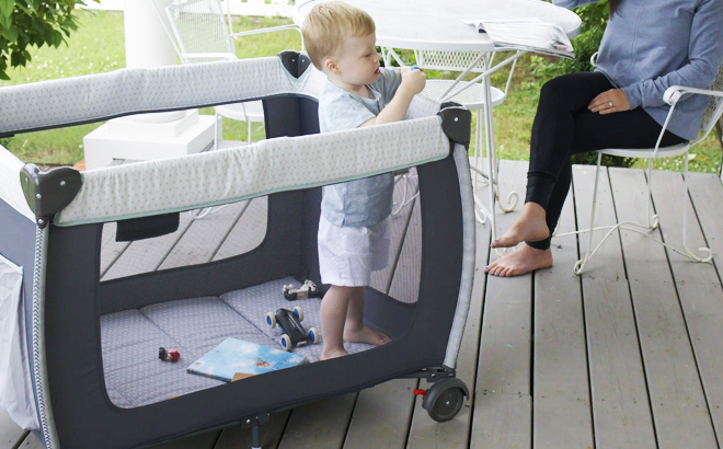 A toddler playing inside a Monbebe Willow Rocking Baby Play Yard