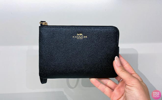 Hand holding Coach Corner Zip Wristlet in Black color