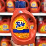 Hand holding one Tide Liquid Laundry Detergent 64 Loads