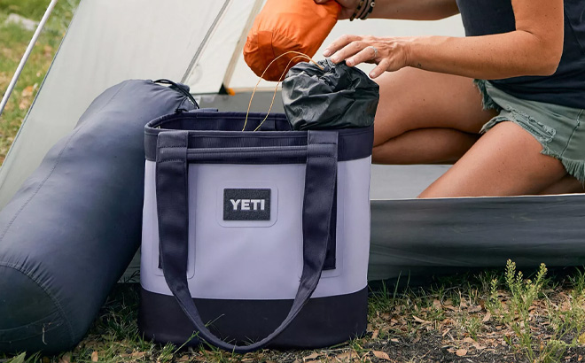 https://www.freestufffinder.com/wp-content/uploads/2023/10/Woman-is-Packing-Stuff-in-to-Yeti-Camino-20-Carryall-Tote-Bag-in-Cosmic-Lilac-Color.jpg