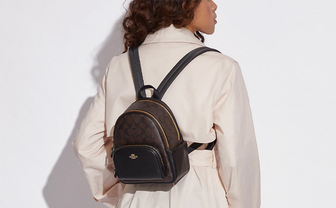 Woman is Wearing Coach Mini Court Backpack In Signature Canvas in Brown Black Color