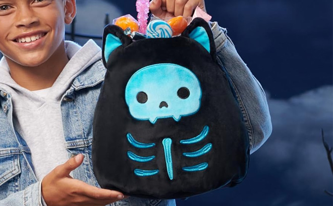 a Boy Carrying a Squishmallows 10 Inch Stump Skeleton Cat Plush Treat Pail