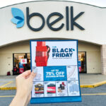 Hand Holding a Belk Black Friday Deals Print in Front of Belk Store