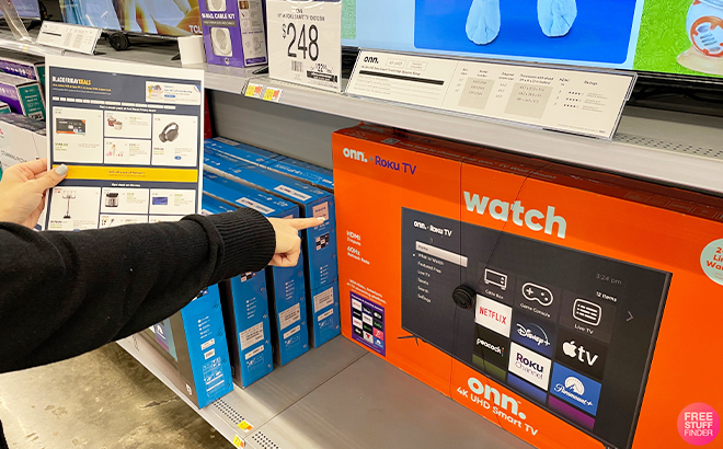 Hand Holding the Walmart Black Friday 2023 Ad in Walmart Pointing at a TV