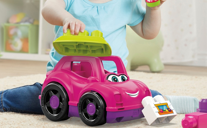 Little Girl Playing with Fisher Price Mega Blocks Building Blocks Catie Convertible Pink Toy Car